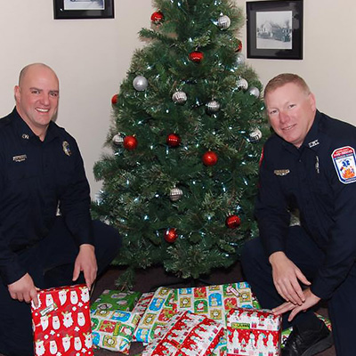 Firefighters with gifts for kids under the Christmas tree
